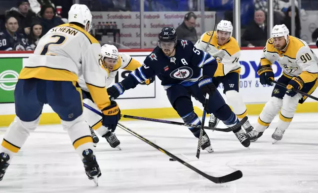 Winnipeg Jets' Mark Scheifele (55) carries the puck past Nashville Predators' Spencer Stastney (24) during second period NHL hockey action in Winnipeg, Canada, Tuesday, Jan. 7, 2025. (Fred Greenslade/The Canadian Press via AP)