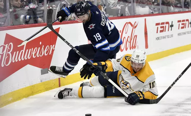 Nashville Predators' Colton Sissons (10) trips up Winnipeg Jets' David Gustafsson (19) during second period NHL hockey action in Winnipeg, Canada, Tuesday, Jan. 7, 2025. (Fred Greenslade/The Canadian Press via AP)