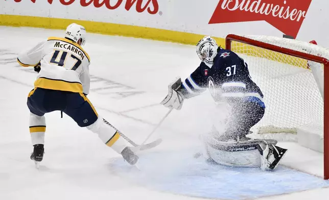 Winnipeg Jets goaltender Connor Hellebuyck (37) makes a save on Nashville Predators' Michael McCarron (47) during the first period of an NHL hockey game in Winnipeg, Manitoba, Tuesday, Jan. 7, 2025. (Fred Greenslade/The Canadian Press via AP)