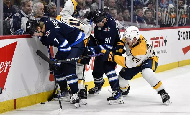 Nashville Predators' Gustav Nyquist (14) and teammate Spencer Stastney (24) battle for the puck with Winnipeg Jets' Vladislav Namestnikov (7) and teammate Cole Perfetti (91) during second period NHL hockey action in Winnipeg, Canada, Tuesday, Jan. 7, 2025. (Fred Greenslade/The Canadian Press via AP)