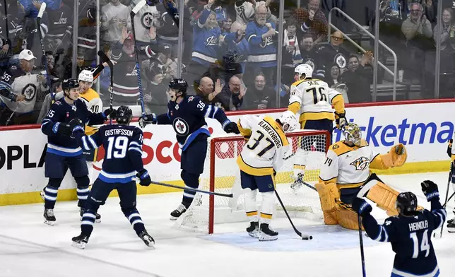 Winnipeg Jets' Morgan Barron (36) celebrates his goal on Nashville Predators goaltender Juuse Saros (74) with teammates David Gustafsson (19) and Rasmus Kupari (15) during the first period of an NHL hockey game in Winnipeg, Manitoba, Tuesday, Jan. 7, 2025. (Fred Greenslade/The Canadian Press via AP)