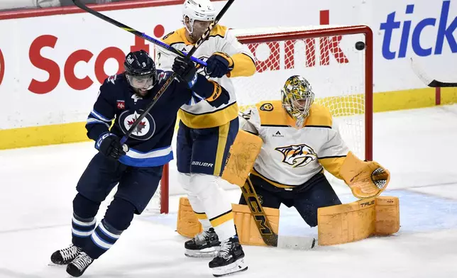 A shot by Winnipeg Jets Josh Morrissey, not shown, gets past Nashville Predators goaltender Juuse Saros (74) for a goal as Predators' Luke Schenn (2) defends against Jets' Alex Iafallo (9) during the first period of an NHL hockey game in Winnipeg, Manitoba, Tuesday, Jan. 7, 2025. (Fred Greenslade/The Canadian Press via AP)