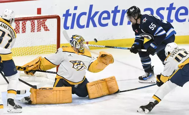 Nashville Predators goaltender Juuse Saros (74) makes a save on a shot by Winnipeg Jets' Mark Scheifele (55) during the first period of an NHL hockey game in Winnipeg, Manitoba, Tuesday, Jan. 7, 2025. (Fred Greenslade/The Canadian Press via AP)