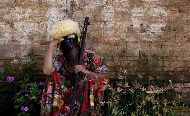 A performer dressed as Bastiao the clown rests amid performing with the Santo Antonio Folia de Reis group during a procession marking Epiphany, or Three Kings Day, in Santo Antonio de Goias, Brazil, Sunday, Jan. 5, 2025. (AP Photo/Eraldo Peres)