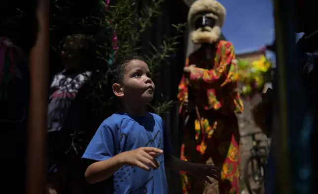 A boy dances with the clown named Bastiao during the arrival of the Santo Antonio Folia de Reis group during a procession marking Epiphany, or Three Kings Day, in Santo Antonio de Goias, Brazil, Saturday, Jan. 4, 2025. (AP Photo/Eraldo Peres)