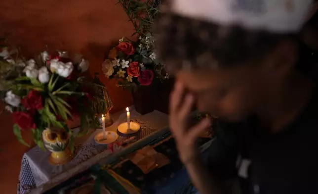 A boy makes the sign of the cross in front of an altar with an image of Our Lady during the arrival of the Santo Antonio Folia de Reis group in Santo Antonio de Goias, Brazil, Saturday, Jan. 4, 2025. (AP Photo/Eraldo Peres)