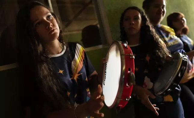 Girls play tambourines during a performance, by the Santo Antonio Folia de Reis group, marking Epiphany, or Three Kings Day, in Santo Antonio de Goias, Brazil, Sunday, Jan. 5, 2025. (AP Photo/Eraldo Peres)