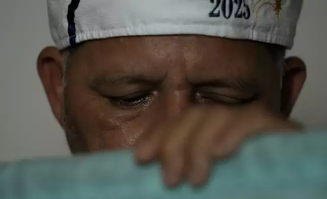 A reveler cries as he receives a flag representing the Three Kings during a procession marking Epiphany, or Three Kings Day, in Santo Antonio de Goias, Brazil, Sunday, Jan. 5, 2025. (AP Photo/Eraldo Peres)