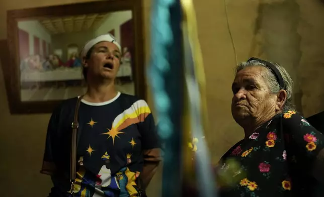 Adelina Rodrigues, right, holds a flag representing the Three Kings during a procession marking Epiphany, or Three Kings Day, in Santo Antonio de Goias, Brazil, Sunday, Jan. 5, 2025. (AP Photo/Eraldo Peres)