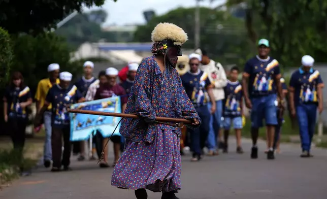 A clown named Bastiao leads the Santo Antonio Folia de Reis group, during a procession marking Epiphany, or Three Kings Day in Santo Antonio de Goias, Brazil, Saturday, Jan. 4, 2025. The procession depicts the Biblical journey of the Three Kings to visit baby Jesus. (AP Photo/Eraldo Peres)