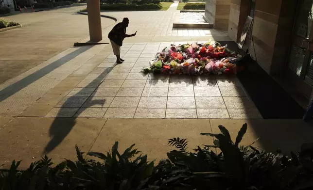 FILE - A woman stops to photograph a memorial for George Floyd at The Fountain of Praise church in Houston, June 9, 2020, in Houston. (AP Photo/Eric Gay, File)