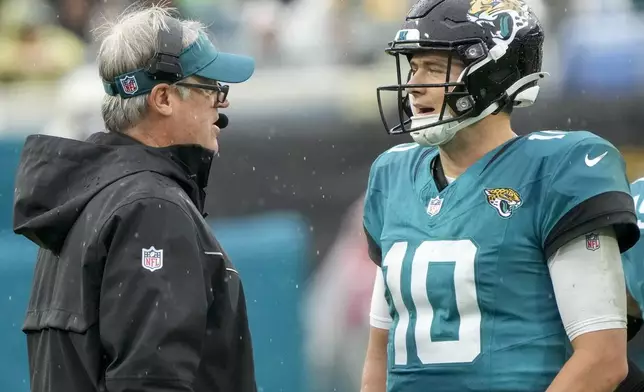 Jacksonville Jaguars head coach Doug Pederson, left, talks to quarterback Mac Jones (10) during the first half of an NFL football game against the Tennessee Titans, Sunday, Dec. 29, 2024, in Jacksonville, Fla. (AP Photo/John Raoux)