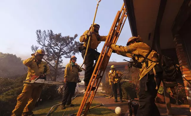 Firefighters prepare for structure protection as the Palisades Fire advances in the Pacific Palisades neighborhood of Los Angeles, Tuesday, Jan. 7, 2025. (AP Photo/Ethan Swope)