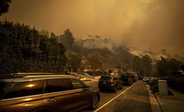 A line of vehicles crowds the road as residents flee from the Palisades Fire in the Pacific Palisades neighborhood of Los Angeles, Tuesday, Jan. 7, 2025. (AP Photo/Ethan Swope)