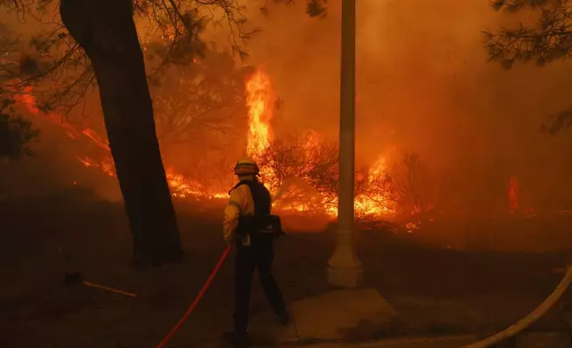 A firefighter battles the advancing Palisades Fire in the Pacific Palisades neighborhood of Los Angeles,Tuesday, Jan. 7, 2025. (AP Photo/Etienne Laurent)