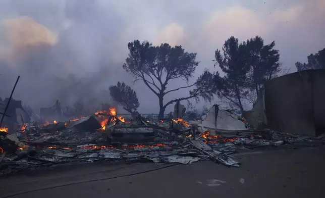 A fire-ravaged property smolder after the Palisades Fire swept through in the Pacific Palisades neighborhood of Los Angeles, Tuesday, Jan. 7, 2025. (AP Photo/Etienne Laurent)