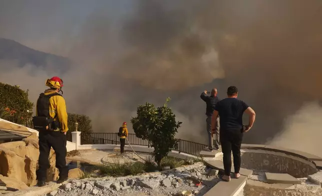 Residents and firefighters watch as the Palisades Fire advances in the Pacific Palisades neighborhood of Los Angeles Tuesday, Jan. 7, 2025. (AP Photo/Etienne Laurent)