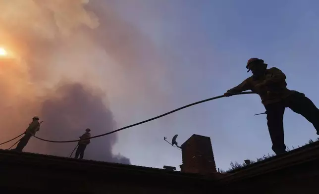 Firefighters prepare for structure protection as the Palisades Fire advances in the Pacific Palisades neighborhood of Los Angeles, Tuesday, Jan. 7, 2025. (AP Photo/Ethan Swope)