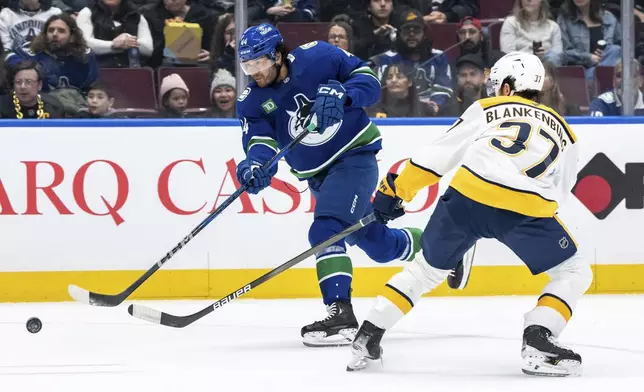 Vancouver Canucks' Kiefer Sherwood (44) shoots the puck as Nashville Predators' Nick Blankenburg (37) defends during the first period of an NHL hockey game in Vancouver, British Columbia, Friday, Jan. 3, 2025. (Ethan Cairns/The Canadian Press via AP)