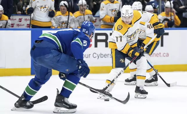 Nashville Predators Luke Evangelista (77) skates with the puck as Vancouver Canucks Tyler Myers (57) defends during the second period of an NHL hockey game in Vancouver, British Columbia, Friday, Jan. 3, 2025. (Ethan Cairns/The Canadian Press via AP)