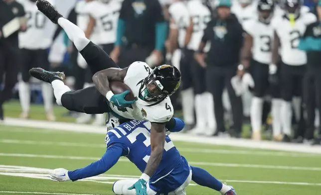 Jacksonville Jaguars running back Tank Bigsby (4) is tackled by Indianapolis Colts safety Julian Blackmon (32) during the first half of an NFL football game, Sunday, Jan. 5, 2025, in Indianapolis. (AP Photo/Darron Cummings)