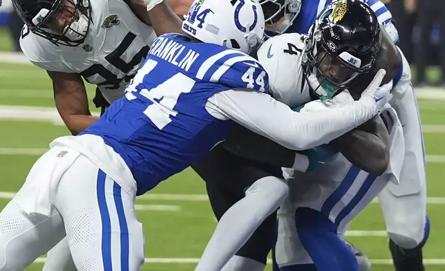 Jacksonville Jaguars running back Tank Bigsby (4) powers through Indianapolis Colts linebacker Zaire Franklin (44) and defensive end Kwity Paye (51) for a touchdown during the first half of an NFL football game, Sunday, Jan. 5, 2025, in Indianapolis. (AP Photo/Darron Cummings)