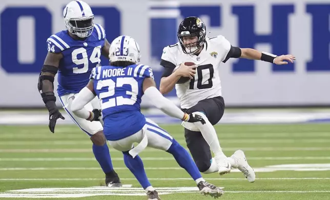 Jacksonville Jaguars quarterback Mac Jones (10) runs with the ball as Indianapolis Colts defensive end Tyquan Lewis (94), and cornerback Kenny Moore II (23) move in during the second half of an NFL football game, Sunday, Jan. 5, 2025, in Indianapolis. (AP Photo/Michael Conroy)