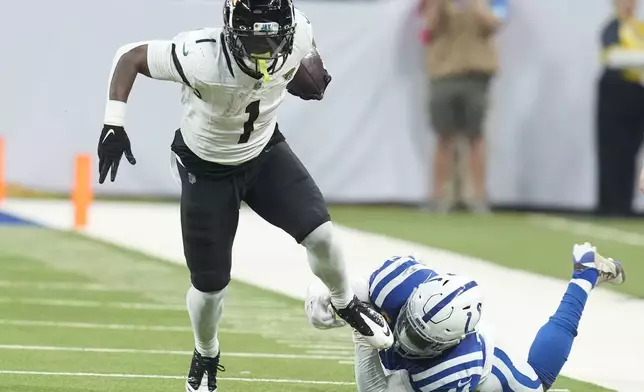 Jacksonville Jaguars running back Travis Etienne Jr. (1) breaks through a tackle by Indianapolis Colts linebacker Zaire Franklin (44) during the first half of an NFL football game, Sunday, Jan. 5, 2025, in Indianapolis. (AP Photo/Darron Cummings)