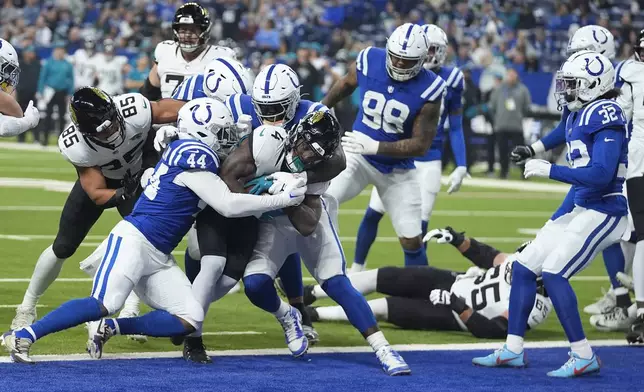 Jacksonville Jaguars running back Tank Bigsby (4) powers through Indianapolis Colts linebacker Zaire Franklin (44) and defensive end Kwity Paye (51) for a touchdown during the first half of an NFL football game, Sunday, Jan. 5, 2025, in Indianapolis. (AP Photo/Darron Cummings)