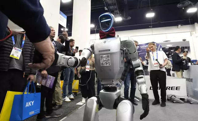 A Unitree H1 robot shakes the hand of an attendee at the CES tech show Wednesday, Jan. 8, 2025, in Las Vegas. (AP Photo/Abbie Parr)