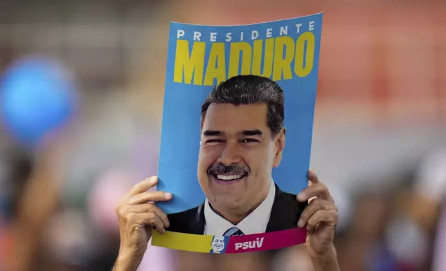 FILE - A supporter displays a poster of President Nicolas Maduro during his closing election campaign rally in Caracas, Venezuela, July 25, 2024. (AP Photo/Fernando Vergara, File)