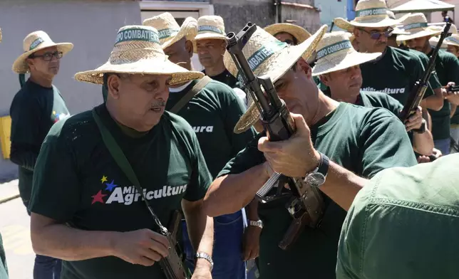 Public workers hold rifles prior to a march of government-backed militias in Caracas, Venezuela, Tuesday, Jan. 7, 2025, days ahead of President Nicolas Maduro's inauguration for a third term. (AP Photo/Matias Delacroix)