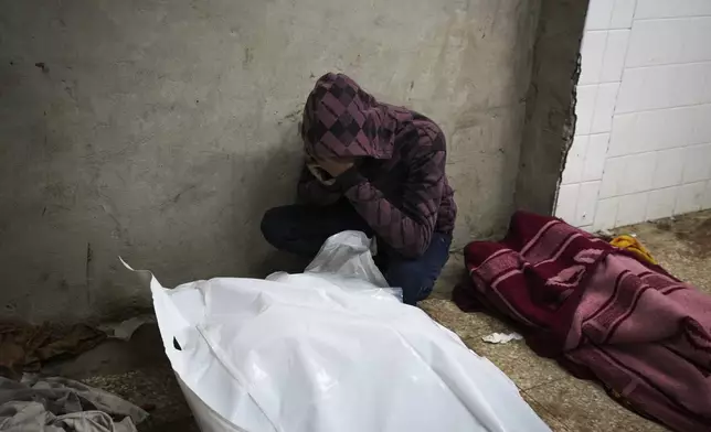 A man mourn over the bodies of two members of Abeid family who were killed in the Israeli bombardment in Maghazi, central Gaza Strip, at Al-Aqsa Martyrs Hospital in Deir al-Balah, Tuesday, Jan. 7, 2025. (AP Photo/Abdel Kareem Hana)