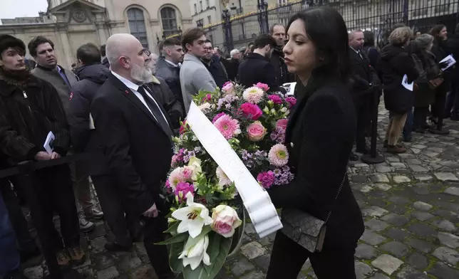 A woman bring a wreath a flowers at Notre Dame du Val-de-Grace church before a public memorial for late far-right leader Jean-Marie Le Pen, Thursday, Jan. 16, 2025 in Paris. Jean-Marie Le Pen, the founder of France's main far-right party, died on Jan.7, 2025 aged 96. (AP Photo/Michel Euler)