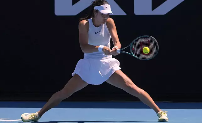 Emma Raducanu of Britain plays a backhand return to Ekaterina Alexandrova of Russia during their first round match at the Australian Open tennis championship in Melbourne, Australia, Tuesday, Jan. 14, 2025. (AP Photo/Asanka Brendon Ratnayake)