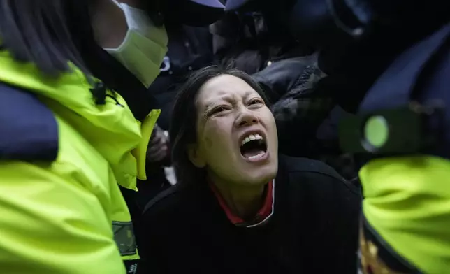 Police officers escort away a supporter of impeached South Korean President Yoon Suk Yeol as Yoon faces potential arrest after a court on Tuesday approved a warrant for his arrest, near the presidential residence in Seoul, South Korea, Thursday, Jan. 2, 2025. (AP Photo/Ahn Young-joon)