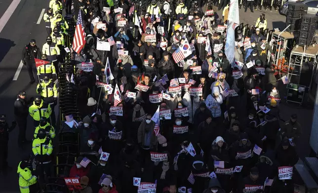 Supporters of impeached South Korean President Yoon Suk Yeol stage a rally to oppose a court having issued a warrant to detain Yoon, as police offices stand guard near the presidential residence in Seoul, South Korea, Friday, Jan. 3, 2025. The letters read, "Oppose Impeachment." (AP Photo/Lee Jin-man)