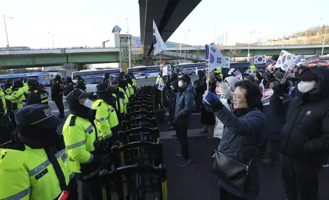 Supporters of impeached South Korean President Yoon Suk Yeol stage a rally to oppose a court having issued a warrant to detain Yoon, as police offices stand guard near the presidential residence in Seoul, South Korea, Friday, Jan. 3, 2025. The letters read "Oppose Impeachment." (AP Photo/Lee Jin-man)