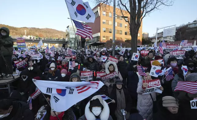 Supporters of impeached South Korean President Yoon Suk Yeol stage a rally to oppose a court having issued a warrant to detain Yoon, as police offices stand guard near the presidential residence in Seoul, South Korea, Friday, Jan. 3, 2025. The letters read "Oppose Impeachment." (AP Photo/Lee Jin-man)