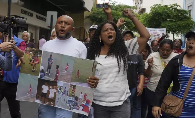 Luis Arroyo, left, carries photos of his two missing sons, Ismael and Josué, who were last seen on Dec. 8 running away from a military convoy with two other youths, as he protests with his family and activists outside the prosecutor's office in Guayaquil, Monday, Dec. 23, 2024. (AP Photo/Cesar Munoz)