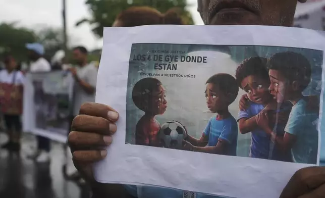 Protesters gather outside the court that is holding a hearing for the soldiers accused of being connected to the disappearance of four children in Guayaquil, Ecuador, Tuesday, Dec. 31, 2024. The sign reads in Spansh: "Where are the four from Guayaquil?" (AP Photo/Cesar Munoz)