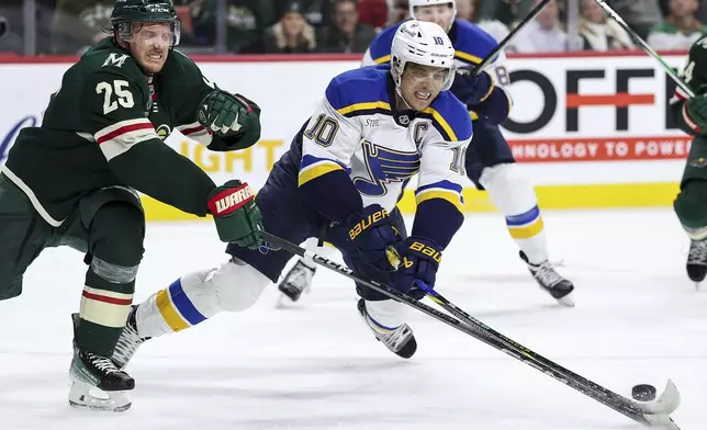 St. Louis Blues center Brayden Schenn, right, and Minnesota Wild defenseman Jonas Brodin reach for the puck during the third period of an NHL hockey game, Tuesday, Jan. 7, 2025, in St. Paul, Minn. (AP Photo/Matt Krohn)