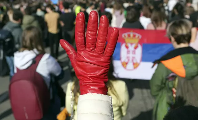 A woman raises a red glove symbolizing blood during a student-led 24 hour block on an intersection to protest the deaths of 15 people killed in the November collapse of a train station canopy, in Belgrade, Serbia, Monday, Jan. 27, 2025. (AP Photo/Darko Vojinovic)
