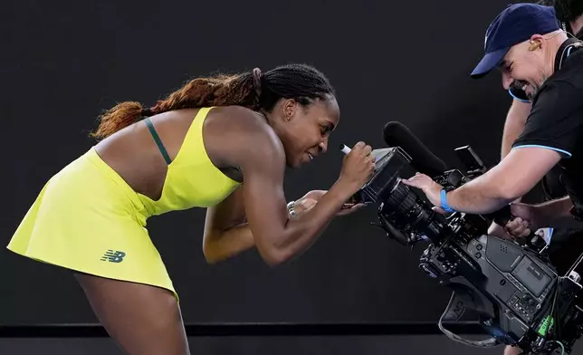 Coco Gauff of the U.S. autographs a tv camera screen after defeating Jodie Burrage of Britain in their second round match at the Australian Open tennis championship in Melbourne, Australia, Wednesday, Jan. 15, 2025. (AP Photo/Vincent Thian)