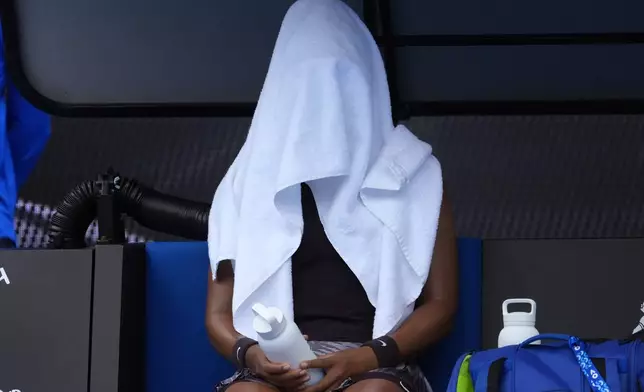 Naomi Osaka of Japan sits with a towel over her during a break in her second round match against Karolina Muchova of the Czech Republic at the Australian Open tennis championship in Melbourne, Australia, Wednesday, Jan. 15, 2025. (AP Photo/Asanka Brendon Ratnayake)