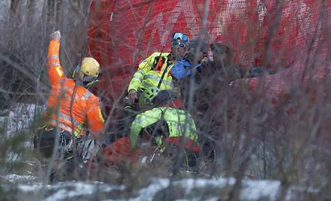 Medical staff are helping France's Cyprien Sarrazin after crashing into protections net during an alpine ski, men's World Cup downhill training, in Bormio, Italy, Friday, Dec. 27, 2024. (AP Photo/Alessandro Trovati)