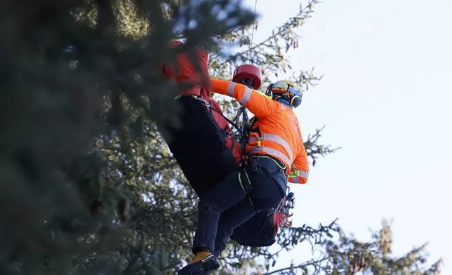 Medical staff are lifting France's Cyprien Sarrazin to an helicopter after crashing into protections net during an alpine ski, men's World Cup downhill training, in Bormio, Italy, Friday, Dec. 27, 2024. (AP Photo/Alessandro Trovati)