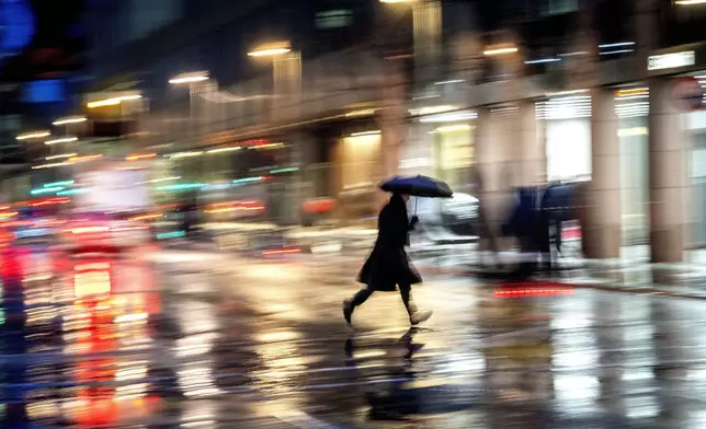 A man crosses the street on a rainy and windy day in Frankfurt, Germany, Thursday, Jan. 2, 2025. (AP Photo/Michael Probst)