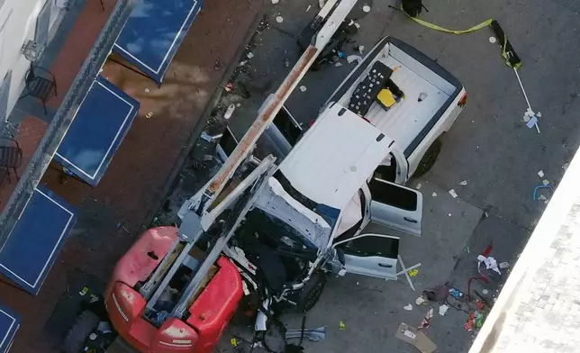 A black flag with white lettering lies on the ground rolled up behind a pickup truck that a man drove into a crowd on Bourbon Street in New Orleans, killing and injuring a number of people, early Wednesday morning, Jan. 1, 2025. The FBI said they recovered an Islamic State group flag, which is black with white lettering, from the vehicle. (AP Photo/Gerald Herbert)