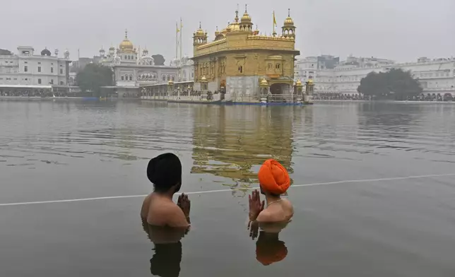 Sikh devotees pray while standing in the pond surrounding the Golden Temple, the holiest shrine for the Sikhs, on New Year's Day in Amritsar, India, Wednesday, Jan. 1, 2025. (AP Photo/Prabhjot Gill)